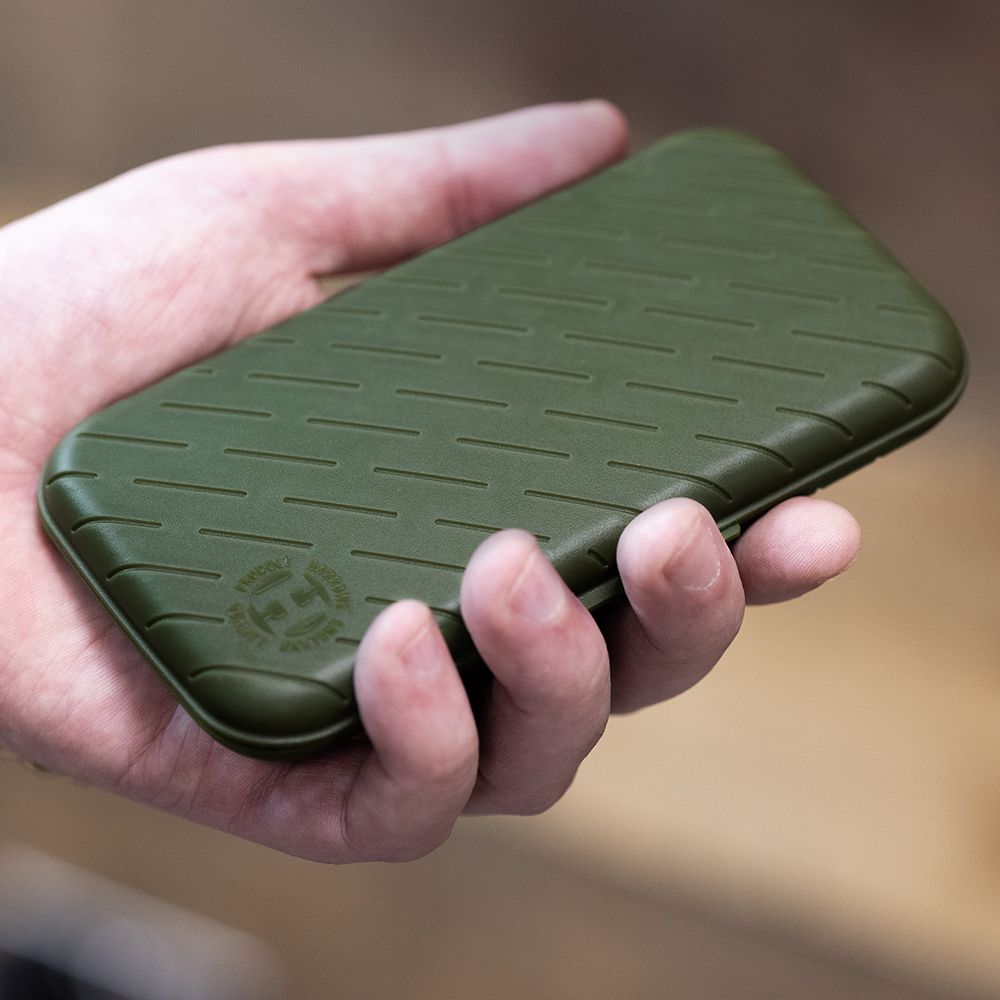 Harrows Slimcase Dart Case Eine Hand hält ein schlankes, grünes Etui. Das Etui hat ein strukturiertes Muster und ein rundes Logo in der Ecke.