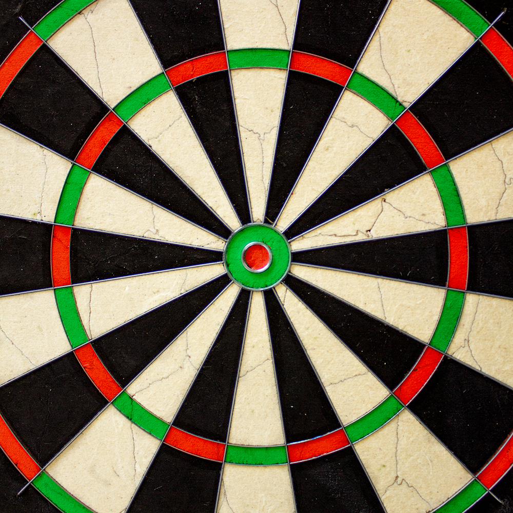 NPQ Steeldartboard Das Bild zeigt das Produkt 'NPQ Steeldartboard'. Es handelt sich um eine klassische Dartscheibe mit schwarzen, weißen, roten und grünen Segmenten.