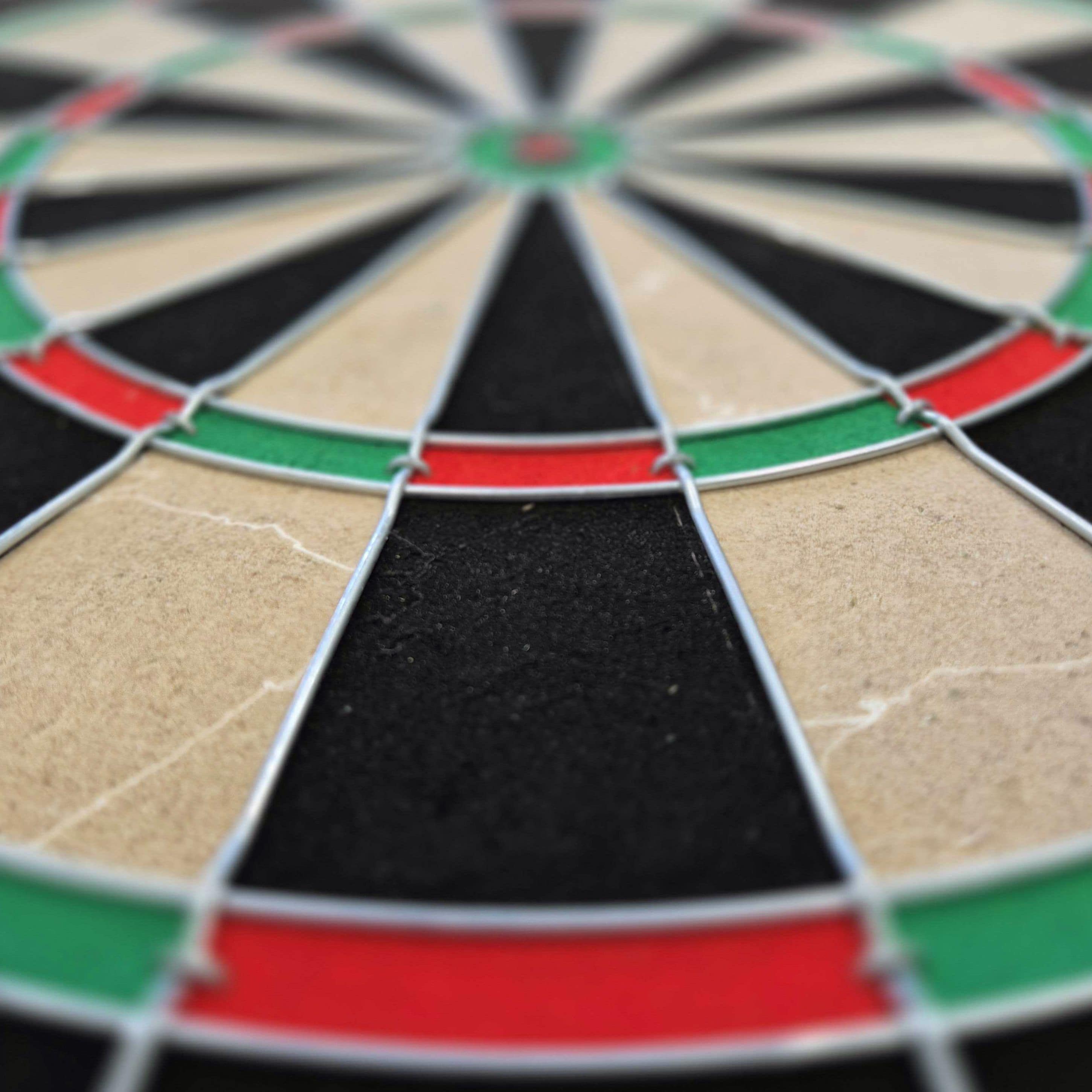 Target Dimitri Van Den Bergh steel dartboard set Target Dimitri Van Den Bergh Steeldartboard Set ist vollständig sichtbar. Das Board steht im Vordergrund.