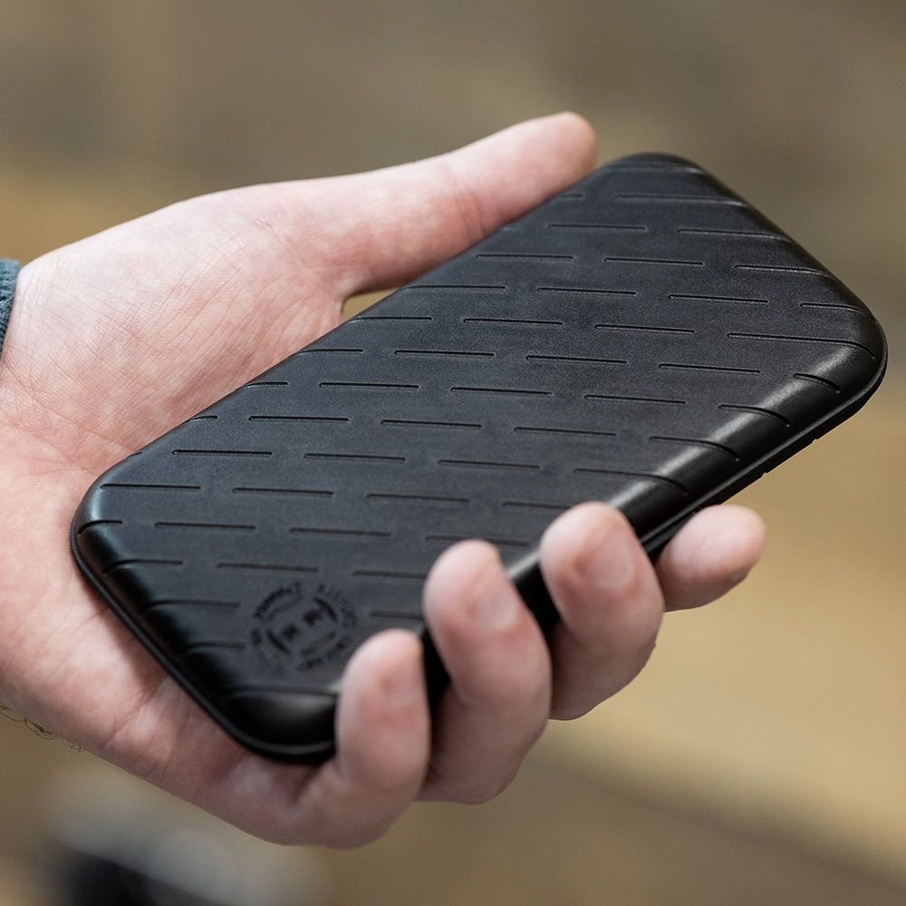 Harrows Slimcase Dart Case Eine Person hält eine schwarze, schlanke Darttasche in der Hand. Die Oberfläche der Tasche hat ein dezentes, gerilltes Muster.