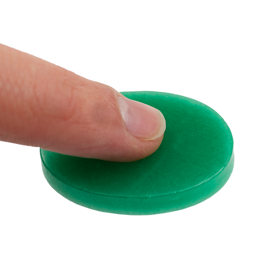 604_Fingerwachs_2 Auf dem Bild sieht man einen Finger, der auf eine grüne Scheibe Fingerwachs drückt. Das Produkt wird zum Schutz und zur Pflege der Finger verwendet.