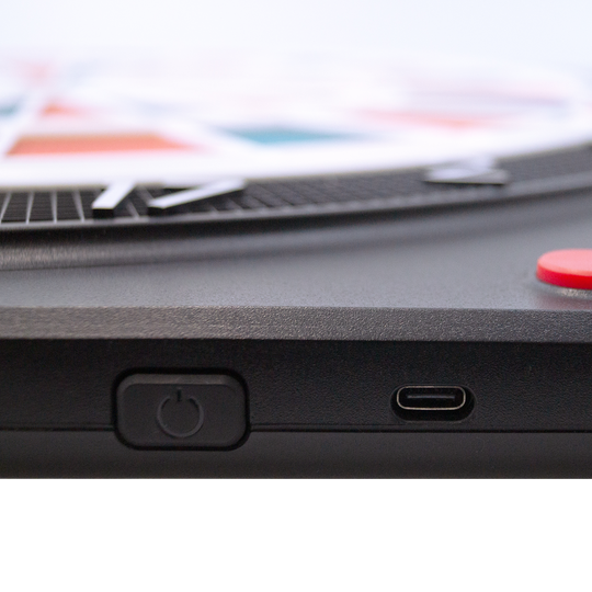 Karella CB-Smart Electronic Soft Dartboard Das Bild zeigt einen Ausschnitt der Karella CB-Smart Elektronische Soft-Dartscheibe. Zu sehen sind der Ein-/Ausschalter und ein USB-C Anschluss an der Seite des Geräts.
