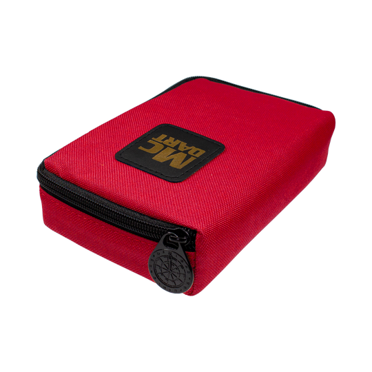 712_McDart_Tasche_Klein_Rot_2 Auf dem Bild ist eine kleine, rote Tasche mit Reißverschluss zu sehen. Auf der Tasche befindet sich ein schwarzes Patch mit der goldenen Aufschrift "MC DART".