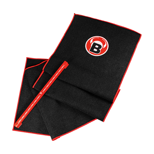 Das Bild zeigt das Bulls Oky System Set, bestehend aus einem schwarzen Teppich mit rotem Rand und einem Metall Oche. Auf dem Teppich ist ein rundes Logo mit einem "B" zu sehen.