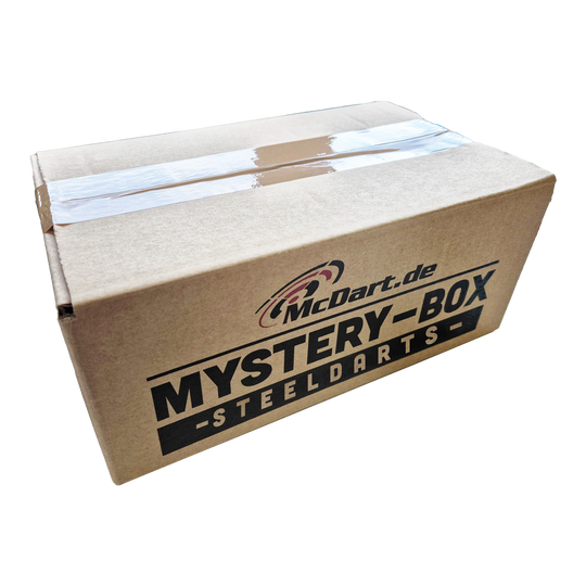 McDart Mystery Box - Steeldarts Auf dem Bild ist ein Karton mit der Aufschrift "McDart.de Mystery-Box - Steeldarts" zu sehen. Die Box ist oben mit Klebeband verschlossen.
