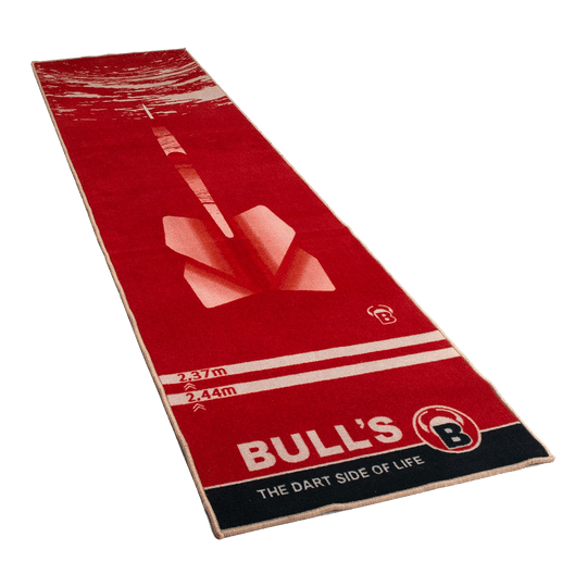 67806_Bulls_Dartteppich_180_Red_1 Dies ist ein roter Teppich mit einem großen Dartpfeil-Motiv in der Mitte. Am unteren Rand steht „BULL'S – THE DART SIDE OF LIFE“.