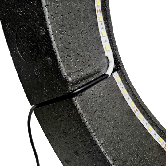 Bulls NL Lumo Light Surround lighting system Das Bild zeigt das „Bulls NL Lumo Light Surround Beleuchtungssystem“ mit LED-Leuchtstreifen auf einer schwarzen, strukturierten Oberfläche. Ein Kabel ist ebenfalls an das Beleuchtungssystem angeschlossen.