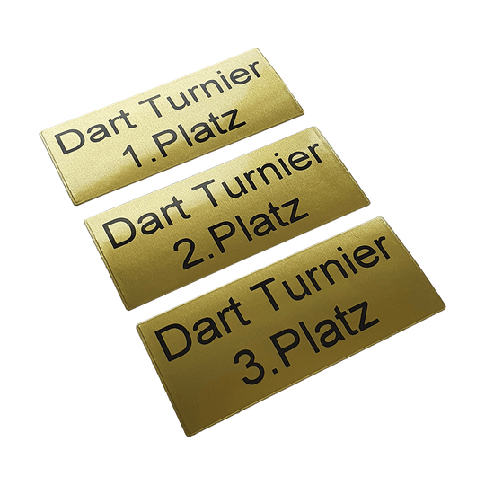 P-Schild_McDart_Pokalschild_mit_Wunschtext_2 Das Bild zeigt drei goldene Pokalschilder mit schwarzer Schrift. Auf den Schildern steht jeweils "Dart Turnier" und der Platz, zum Beispiel "1. Platz", "2. Platz" und "3. Platz".