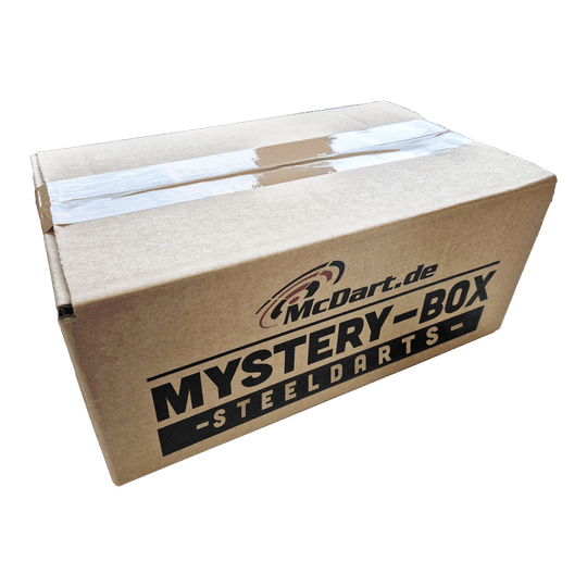 Phil Taylor Mystery Soft Dart Fan Box Auf dem Bild ist ein Karton mit der Aufschrift "McDart.de Mystery-Box Steeldarts" zu sehen. Die Box ist mit durchsichtigem Klebeband verschlossen.